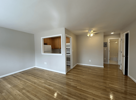 A room with wooden floors and a small kitchenette in the corner.