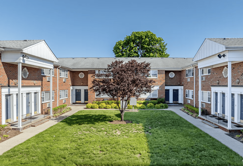 A tree in front of a building with a white roof.