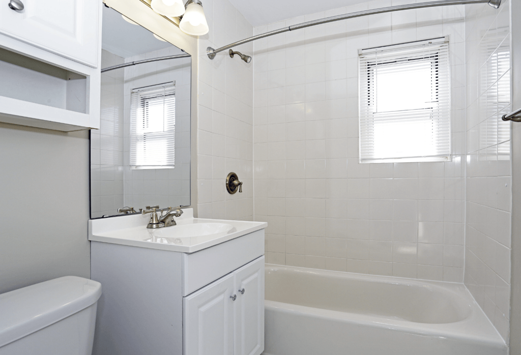 A white bathroom with a tub, sink, and mirror.