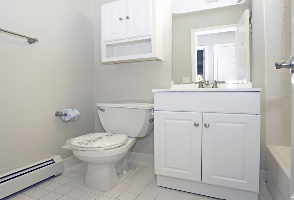 A white toilet sits in a bathroom next to a white cabinet.