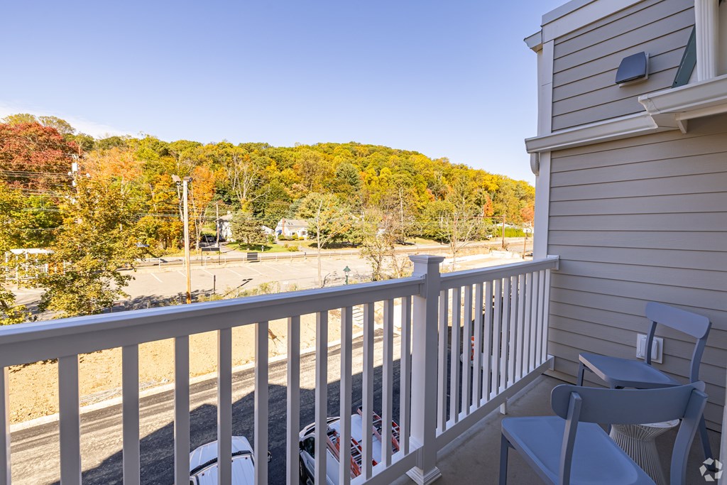 A balcony with a chair and a table overlooking a street.