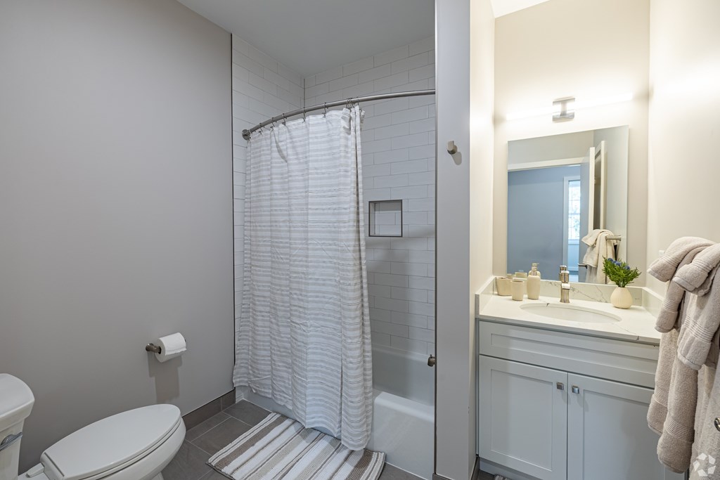 A white bathroom with a toilet, sink, and shower.