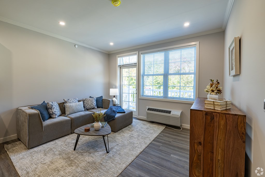 A living room with a grey couch, a coffee table, and a window.