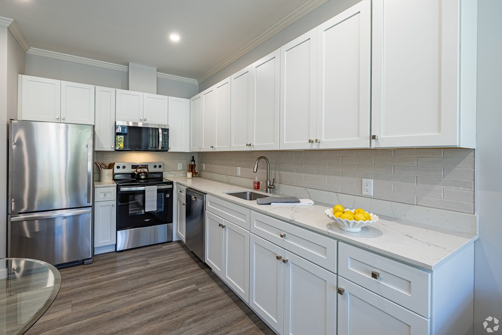 A modern kitchen with white cabinets and a stainless steel refrigerator.