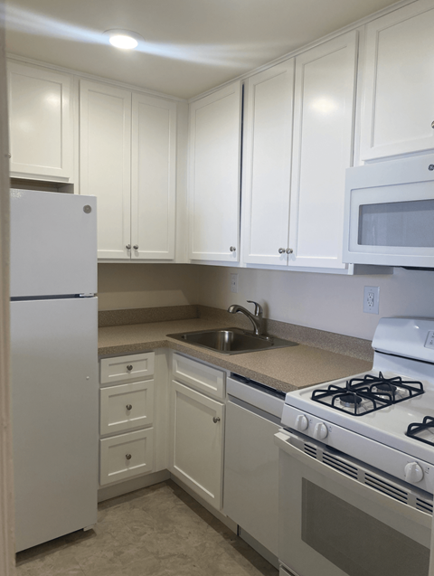 A kitchen with white cabinets and appliances.