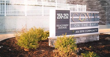 Exterior Sign with logo and address with plants in front of building