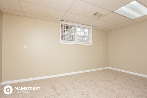 the spacious living room of this manufactured home has a large window and beige carpet