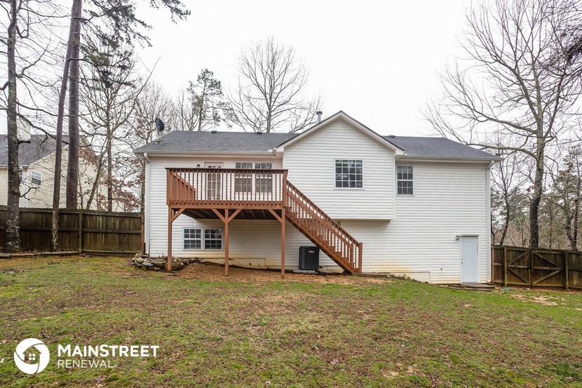 the back of a white house with a deck and a wooden fence