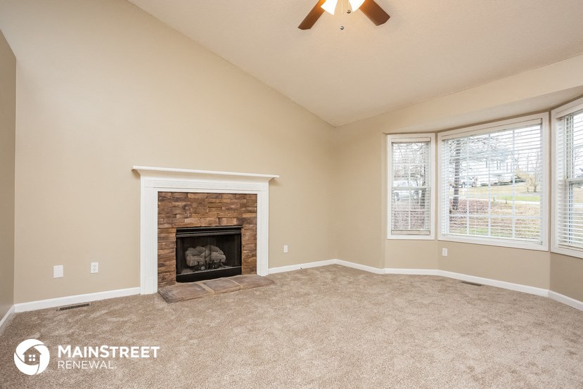 the living room has a fireplace and large windows
