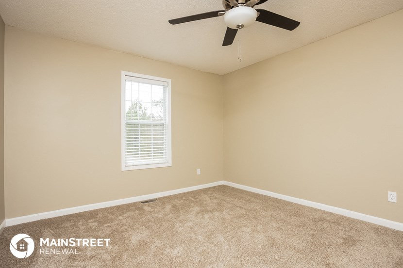 the upstairs bedroom has a ceiling fan and beige carpet