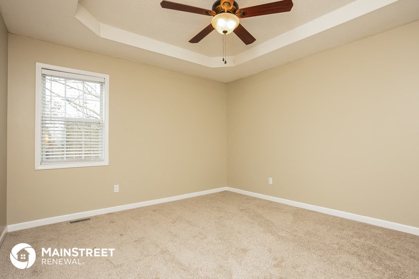 the master bedroom has a carpeted floor and a ceiling fan