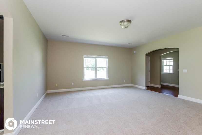 an empty living room with white carpet and a window