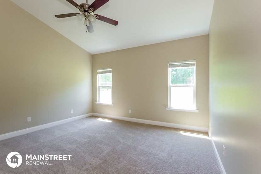 an empty room with a ceiling fan and two windows