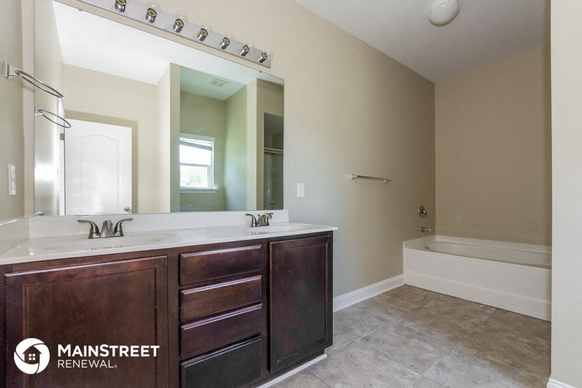 a bathroom with a large mirror and a sink and a tub