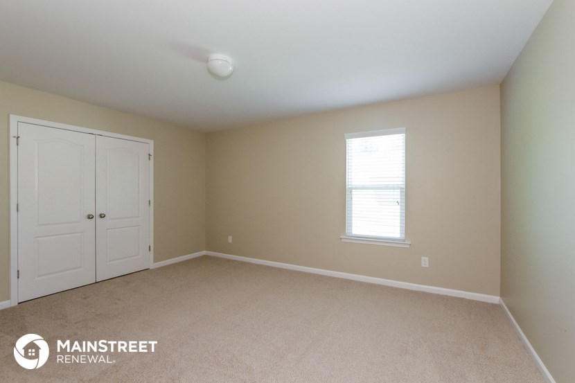 a bedroom with a carpeted floor and a window and two white doors