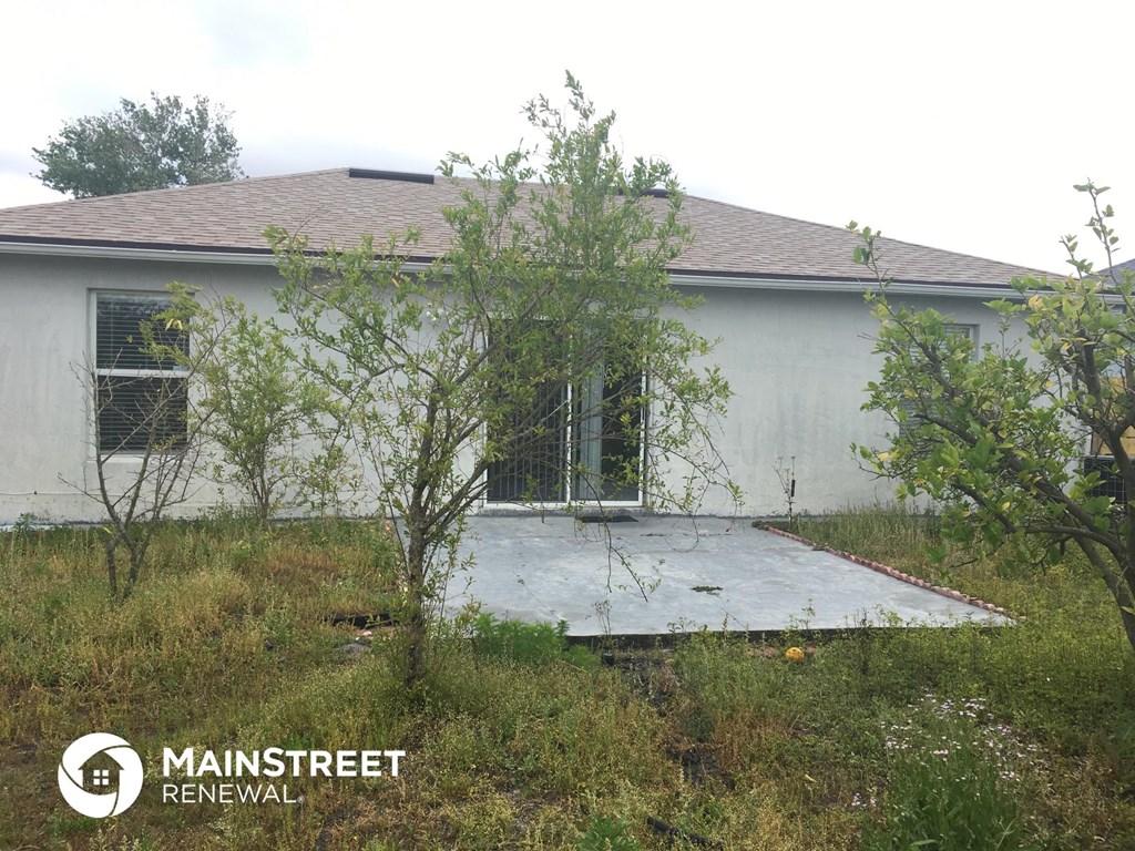 the front of a white house with a patio in the grass