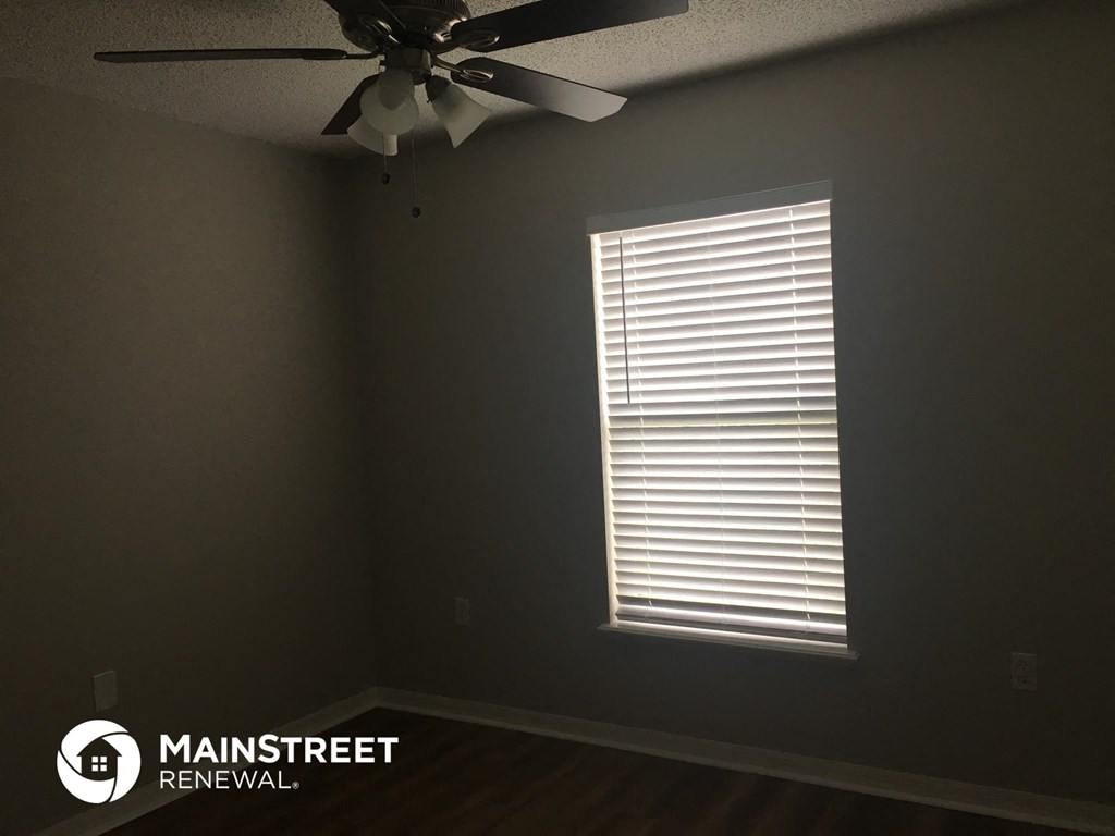 a room with a ceiling fan and a window with blinds