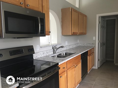 a kitchen with black appliances and granite counter tops and wooden cabinets