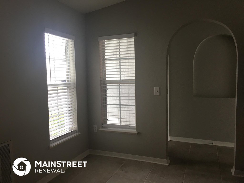 an empty room with two windows with white shutters