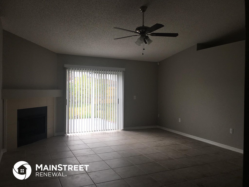 an empty living room with a ceiling fan and a window
