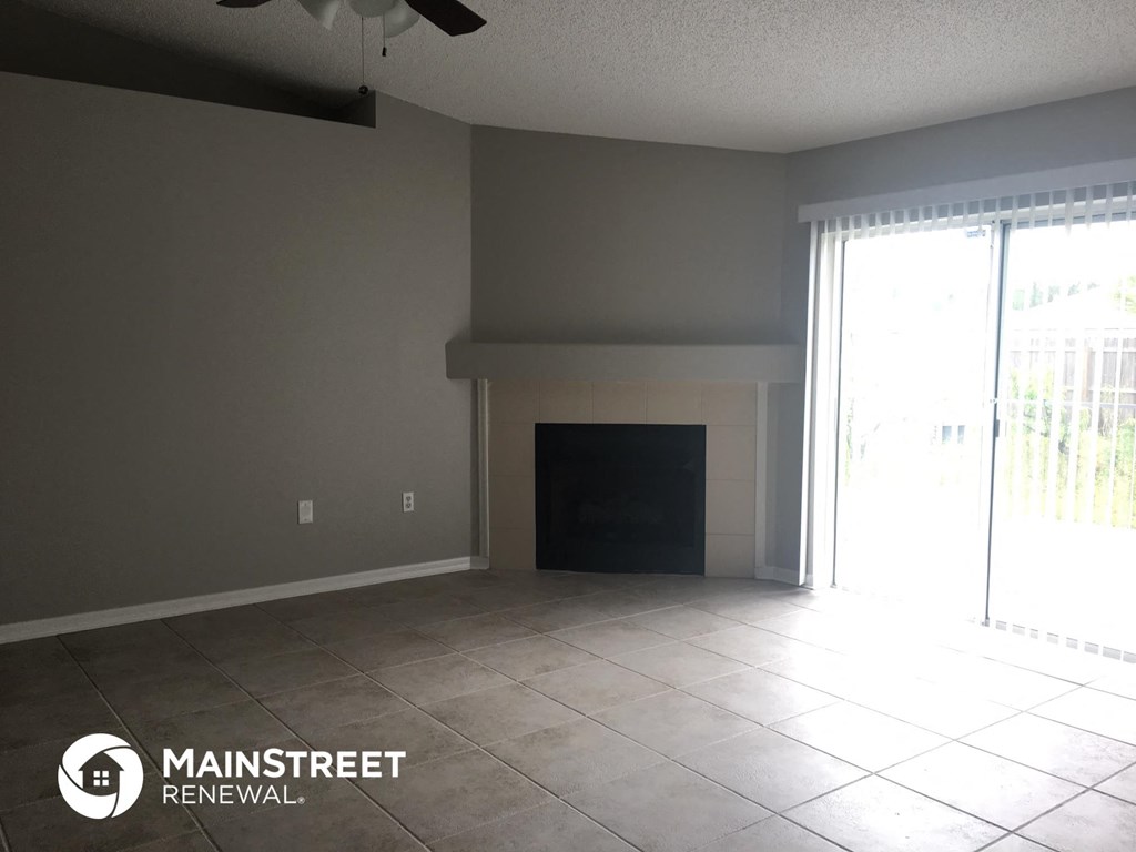 an empty living room with a fireplace and a sliding glass door