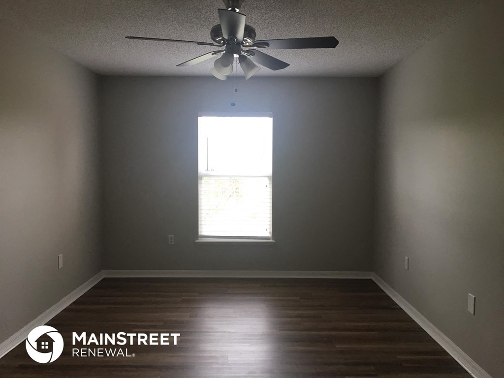 an empty room with a ceiling fan and a window
