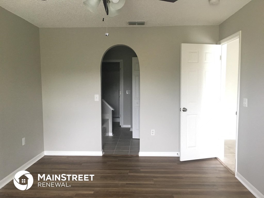 a living room with a hard wood floor and an arched doorway