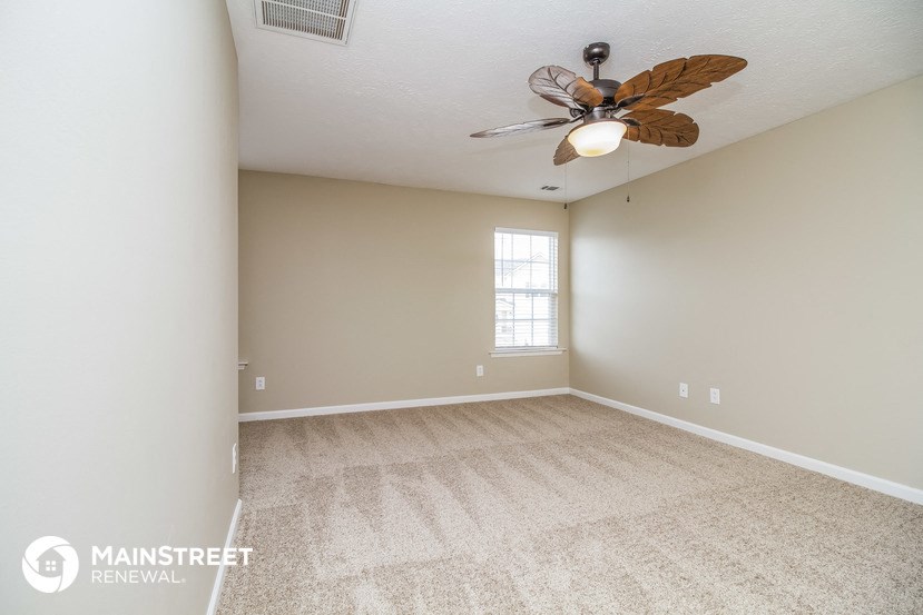 the spacious living room with carpeting and a ceiling fan