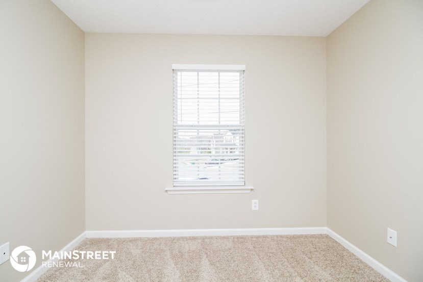 a bedroom with a window and a carpeted floor
