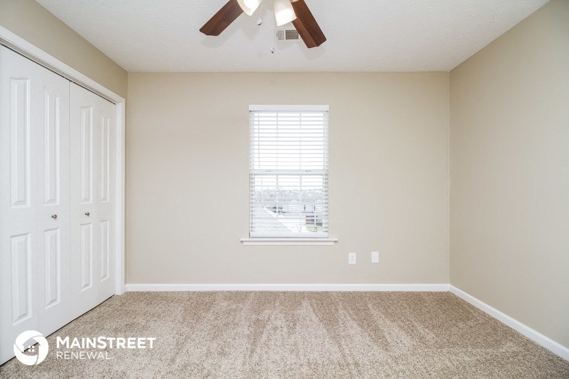 the master bedroom has carpeted floors and a ceiling fan