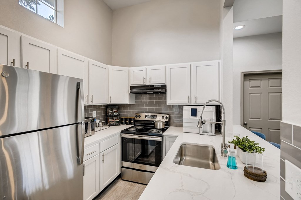 an updated kitchen with stainless steel appliances and white cabinets