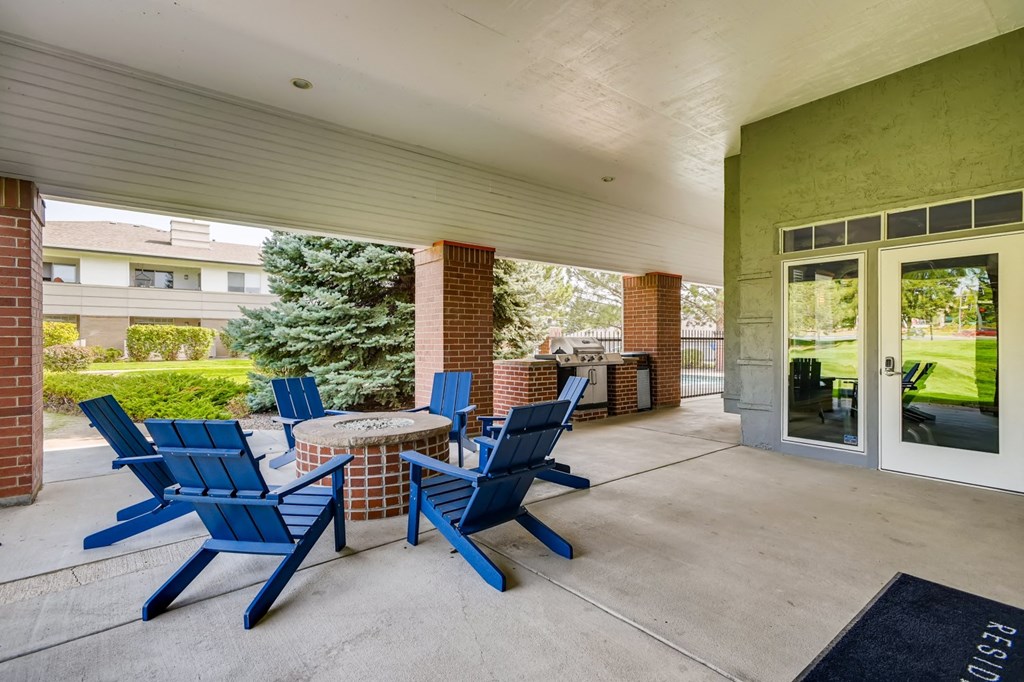 a patio with blue chairs and a table with a fire pit