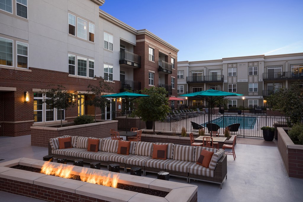 a lounge area with a fire pit in front of an apartment building