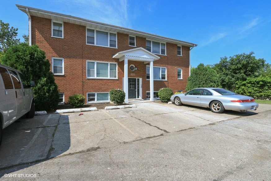 a large brick house with a parking lot and a silver car