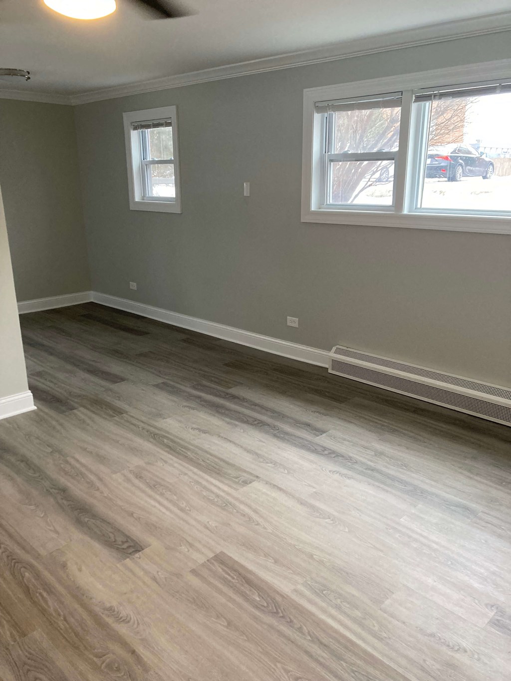 a living room with wood floors and gray walls and a window