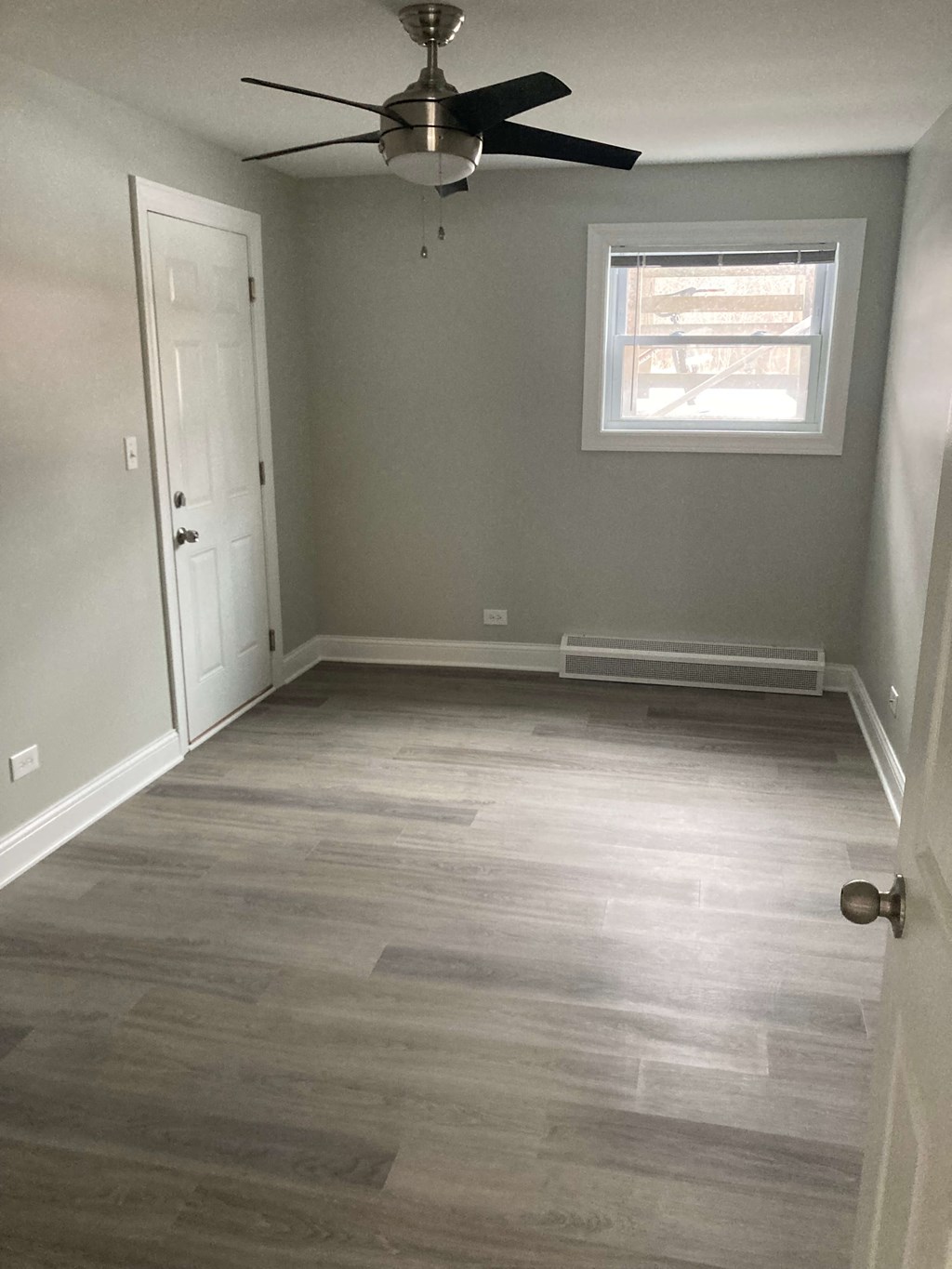 an empty room with wooden floors and a ceiling fan