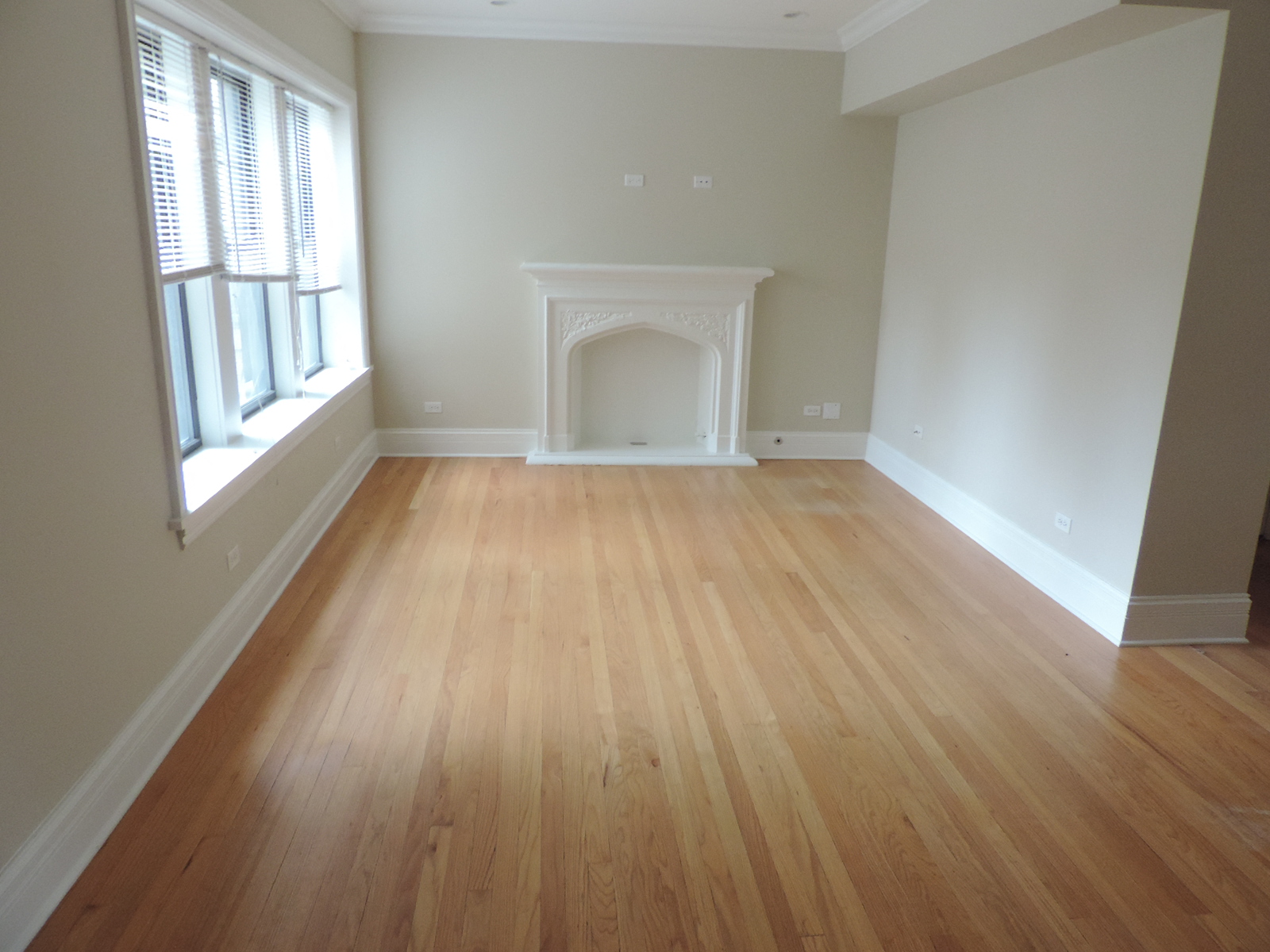 an empty living room with wooden floors and a fireplace