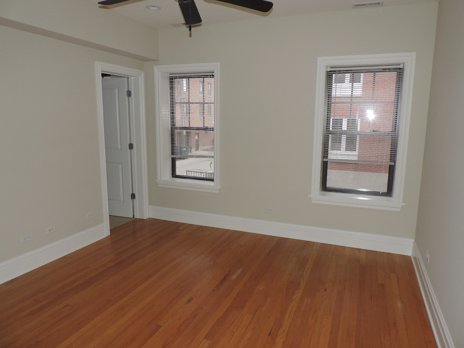 an empty living room with wood floors and two windows