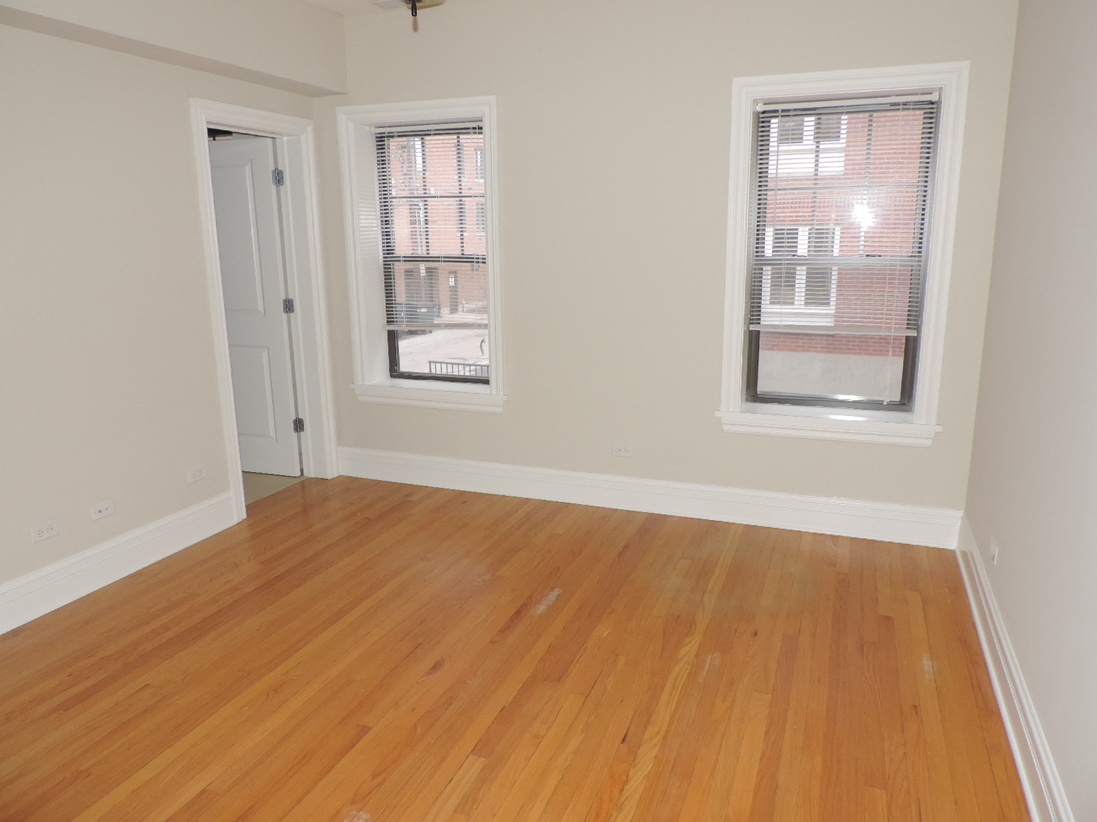 an empty living room with wood floors and two windows