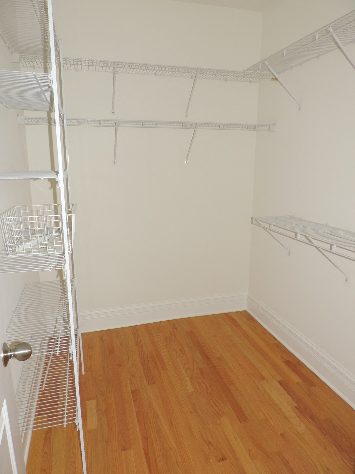 a room with wooden floors and a closet with white walls and shelves