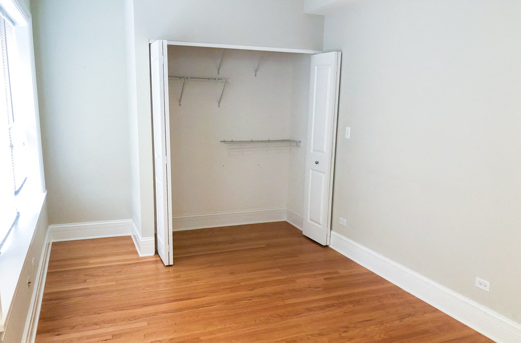 an empty bedroom with wood flooring and a closet