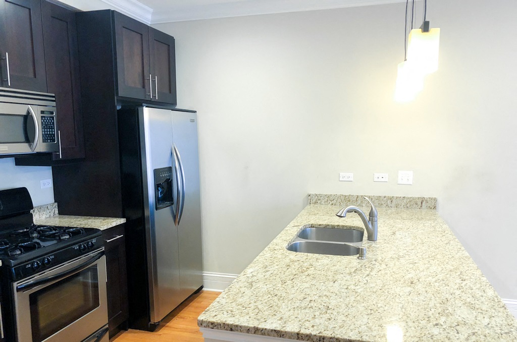a kitchen with a granite counter top and a stainless steel refrigerator