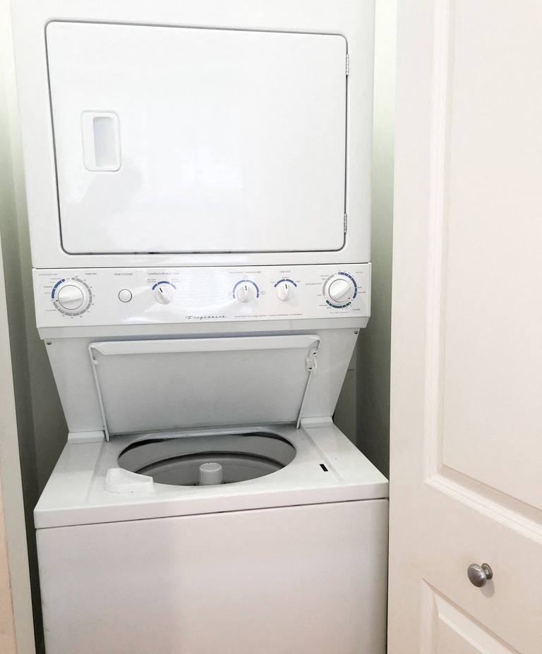 a white washer and dryer in a bathroom with a white door