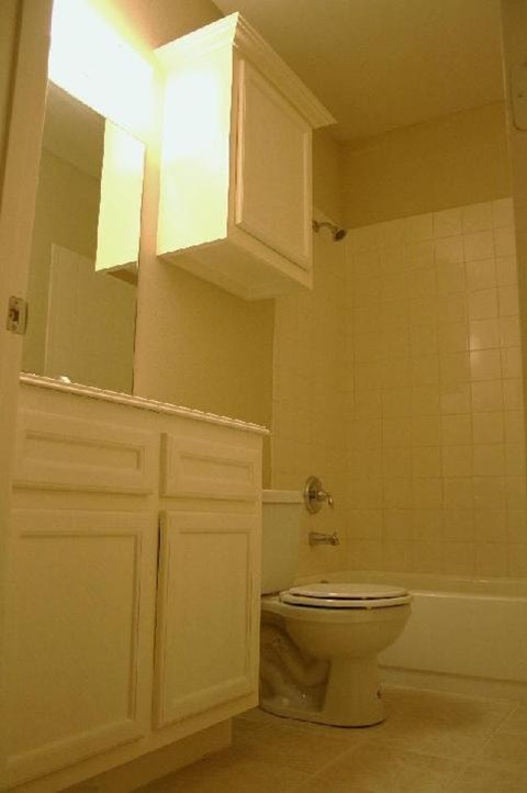 A white toilet sits in a bathroom with a white cabinet and a white door.