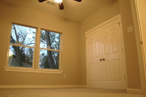 A room with a white door and a window with trees visible outside.