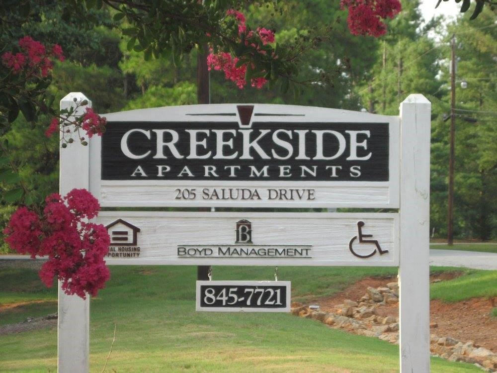 a sign that reads creekside apartments in front of a yard