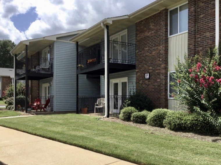 a building with two balconies and a lawn in front of it