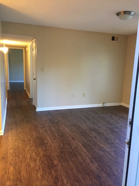 an empty living room with wood flooring and white walls