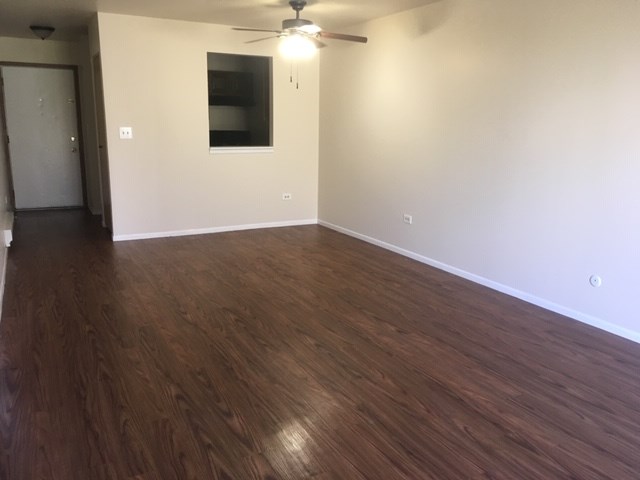 an empty living room with wooden floors and a ceiling fan