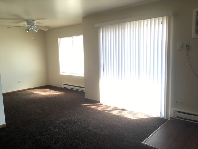 an empty living room with a window and a ceiling fan